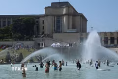 Người dân tránh nóng tại đài phun nước ở Paris, Pháp. (Ảnh: THX/TTXVN)