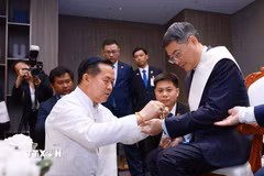 Thủ tướng Lê Minh Hưng thực hiện nghi thức buộc chỉ cổ tay truyền thống của Lào. (Ảnh: Dương Giang/TTXVN)