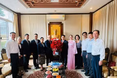 Tổng Lãnh sự Khamphay Phanthongdy trao lẵng hoa tươi thắm chúc mừng Tổng Lãnh sự Đinh Hoàng Linh, phu nhân và tập thể cán bộ nhân viên Tổng Lãnh sự quán Việt Nam. (Ảnh: PV/Vietnam+)