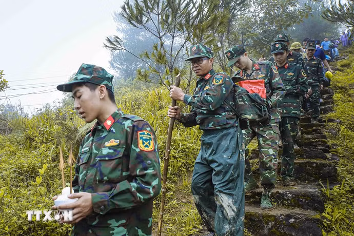 Trên cung đường núi hiểm trở, chiến sỹ cõng hài cốt liệt sỹ xuống núi sau khi hoàn thành công tác quy tập tại bản Lồng, xã Quài Tở, tỉnh Điện Biên. (Ảnh: Xuân Tư/TTXVN)