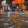 Người dân di chuyển trong điều kiện ngập nước do mưa lớn chiều tối ngày 1/10. (Ảnh: Hồng Đạt/TTXVN)