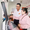 Hướng dẫn người dân thực hiện các thủ tục trên hệ thống điện tử. (Ảnh: Văn Sĩ/TTXVN)
