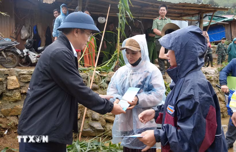 Phó Chủ tịch UBND tỉnh Quảng Ngãi Đỗ Tâm Hiển tặng quà, động viên các hộ dân bị tốc mái hoàn toàn tại xã Măng Ri. (Ảnh: Dư Toán/TTXVN)