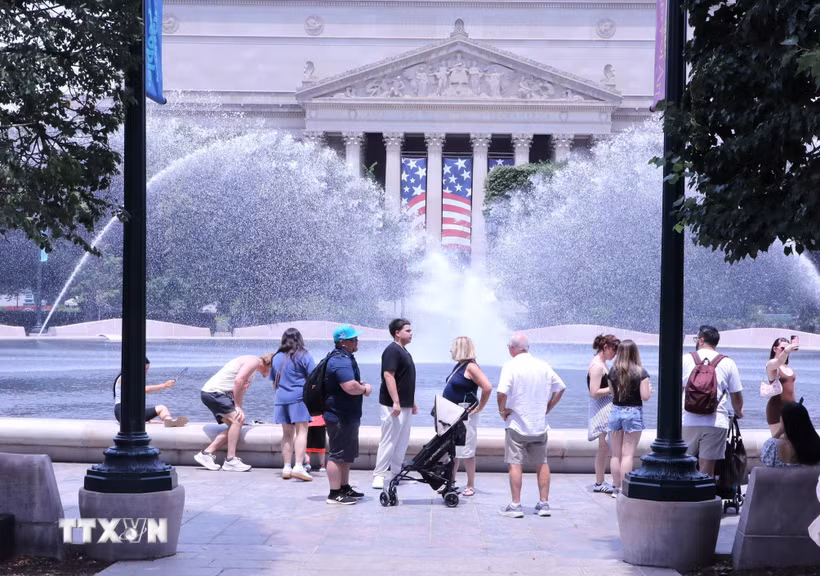 Du khách tránh nắng nóng bên đài phun nước tại khu vực National Mall (Quảng trường Quốc gia) ở thủ đô Washington D.C. (Ảnh: Ngọc Quang/TTXVN)