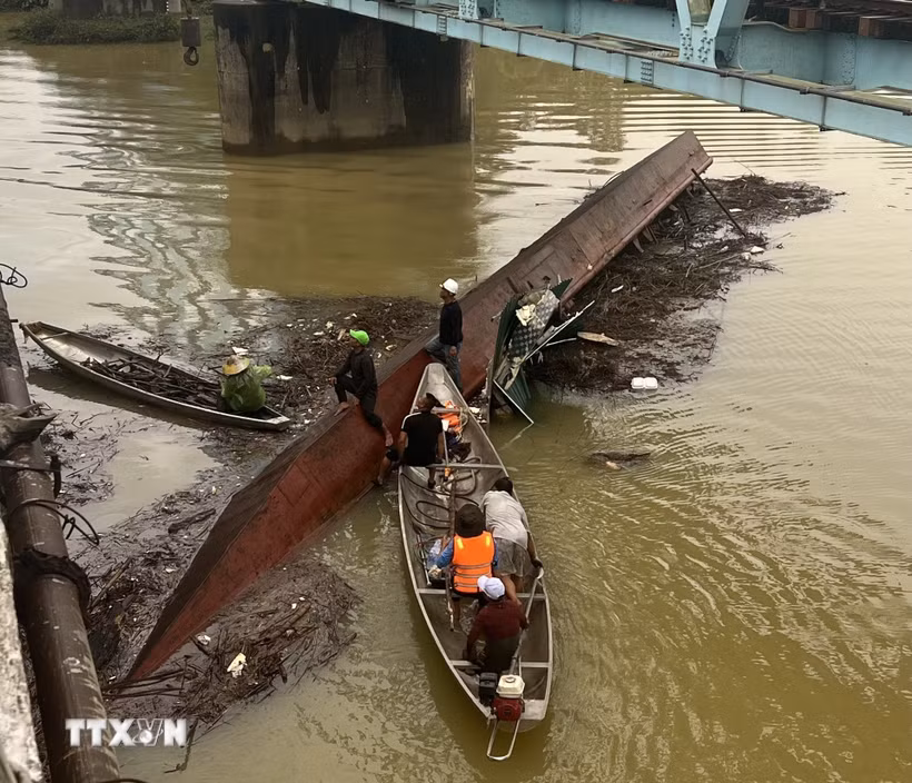 Sà lan bị chìm tại chân cầu Mỹ Chánh được lực lượng cứu hộ dùng cần cẩu kéo nổi, trục vớt an toàn. (Ảnh: Nguyên Linh/TTXVN)