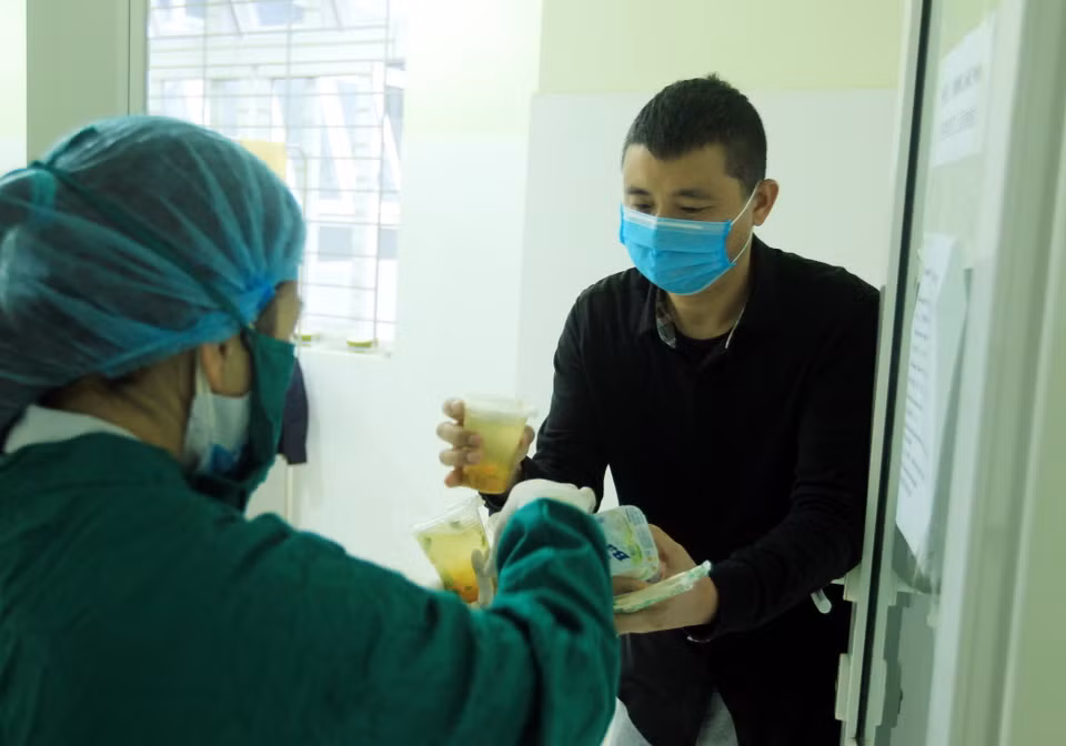 Công dân Trung Quốc nhận những suất ăn của các y bác sỹ mang đến từng phòng. (Ảnh: An Đăng/TTXVN)