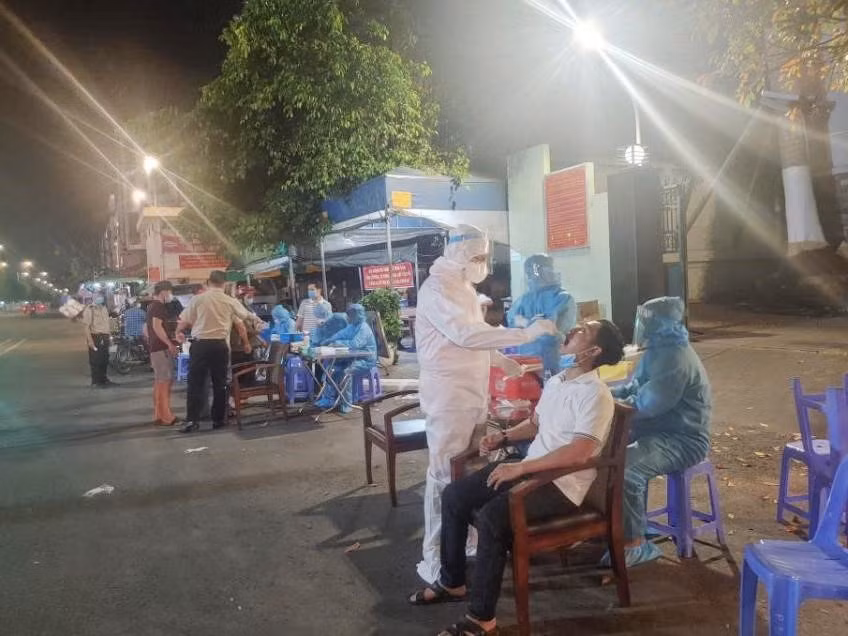 Nhân viên Trung tâm Y tế Thành phố Thủ Đức, Thành phố Hồ Chí Minh lấy mẫu xét nghiệm cho tiểu thương chợ đầu mối Thủ Đức tối Mùng 1 Tết. (Ảnh: TTXVN phát)