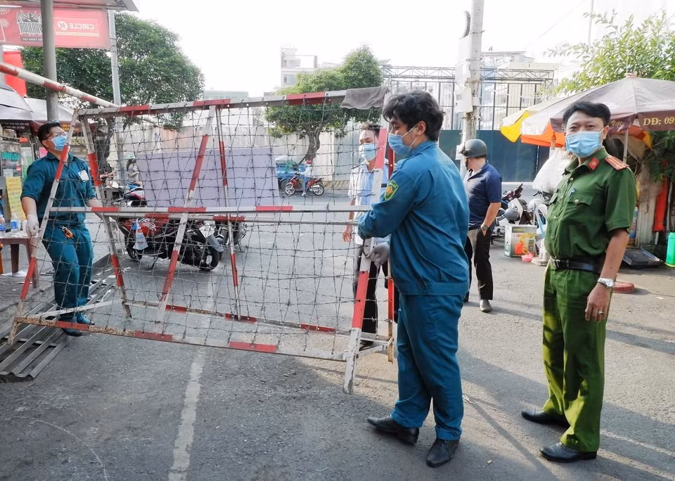 Lực lượng chức năng Phường Nguyễn Cư Trinh, Quận 1 gỡ bỏ phong tỏa tại hẻm 245 Nguyễn Trãi chiều mùng 4 Tết. (Ảnh: TTXVN phát)