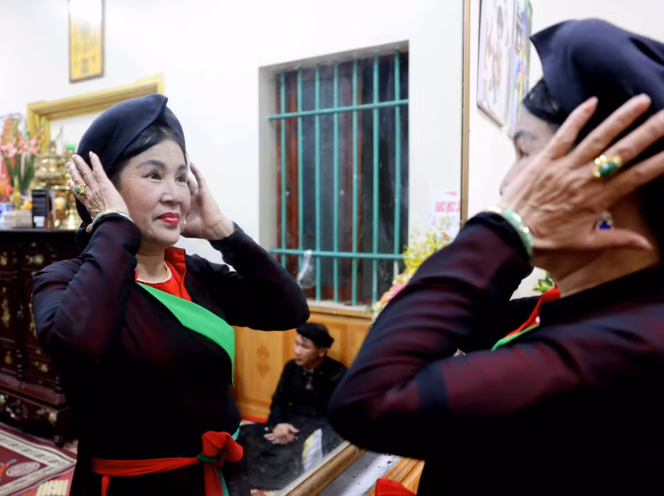 Chị hai vấn lại chiếc khăn mỏ quạ để chuẩn bị vào canh hát. (Ảnh: Nhật Anh/TTXVN)