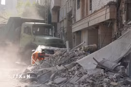 Nhân viên cứu hộ dọn đống đổ nát của tòa nhà bị sập tại Tehran, Iran sau các cuộc không kích của Israel. (Ảnh: THX/TTXVN)