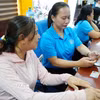 Các cán bộ, nhân viên Bảo hiểm xã hội tỉnh Gia Lai hỗ trợ, hướng dẫn người tham gia bảo hiểm sử dụng ứng dụng VssID. (Ảnh: Quang Thái/TTXVN)