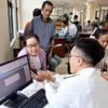 Cán bộ Thuế cơ sở 7 (Thuế An Giang) hướng dẫn người dân thủ tục thuế. (Ảnh: Phạm Hậu/TTXVN)