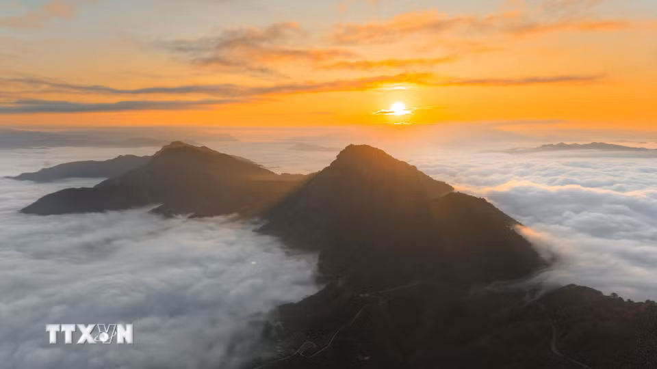 Mặt trời dần nhô lên sau dãy núi, những tia nắng đầu ngày chiếu xuống biển mây trên đỉnh đèo Tằng Quái. (Ảnh: Xuân Tư/TTXVN)