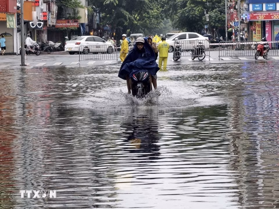 Ngập úng xảy ra trên phố Ngọc Lâm, phường Bồ Đề, khiến việc đi lại của người dân gặp nhiều khó khăn. (Ảnh: Minh Quyết/TTXVN)