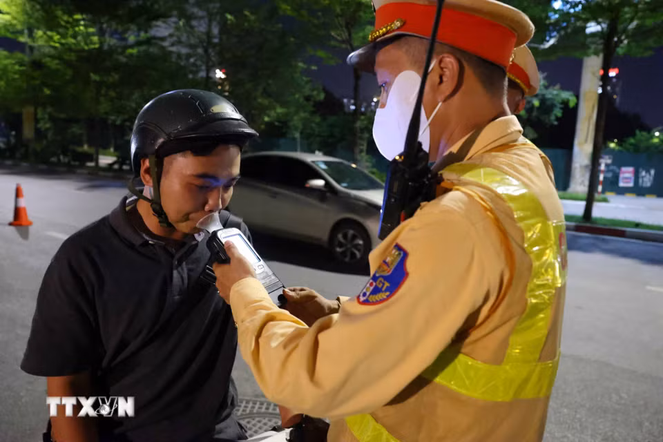 Cán bộ, chiến sỹ đội Cảnh sát giao thông số 6 kiểm tra nồng độ cồn chủ phương tiện tham gia giao thông trong đêm 17 rạng sáng 18/7. (Ảnh: Phạm Kiên/TTXVN)