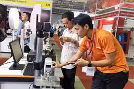 Khách tham quan trải nghiệp ứng dụng điều kiển thiết bị bằng điện thoại thông minh. (Ảnh: Mỹ Phương/TTXVN)