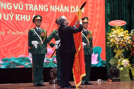 Thường trực Ban Bí thư Trần Quốc Vượng gắn danh hiệu Anh hùng Lực lượng vũ trang nhân dân lên Cờ truyền thống của Văn phòng Khu ủy Khu 5. (Ảnh: Nguyễn Sơn-TTXVN)