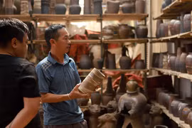 Khách hàng đến xưởng gốm của nghệ nhân Nguyễn Hồng Quang đặt hàng sản phẩm gốm Hương Canh. (Ảnh: Hoàng Hùng/TTXVN)