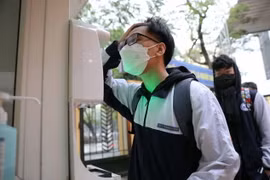 Học sinh lớp 12 trường THPT Trần Nhân Tông, quận Hai Bà Trưng thực hiện đo thân nhiệt khi tới trường học trực tiếp từ sáng 10/1 vừa qua. (Ảnh: Thanh Tùng/TTXVN)