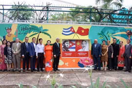 Các đại biểu chụp hình lưu niệm bên bức tranh vẽ cổ động về tình hữu nghị nhân dân Việt Nam-Cuba. (Ảnh: Tiến Lực/TTXVN)