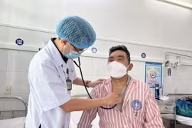 Bác sỹ thăm khám bệnh nhân sau khi nội soi gắp lấy dị vật nằm trong thanh quản. (Ảnh: TTXVN phát)