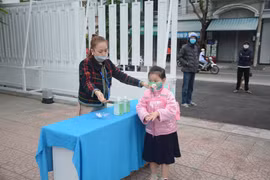 Học sinh lớp 1 trường Tiểu học Võ Thị Sáu, quận Hải Châu, được giáo viên đo thân nhiệt tại cổng trường hồi tháng 12/2021. (Ảnh: Văn Dũng/TTXVN)
