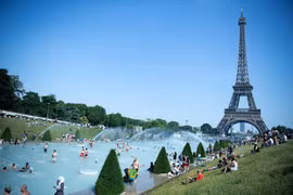 Người dân tại Paris (Pháp) tránh nóng tại các vòi phun nước ở gần tháp Eiffel. (Ảnh: THX/TTXVN)