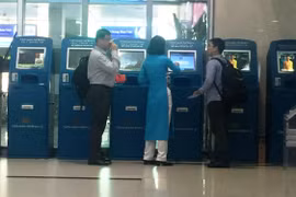 Nhân viên Vietnam Airlines hướng dẫn khách làm thủ tục trực tuyến tại kiosk check-in. (Ảnh: Việt Hùng/Vietnam+)