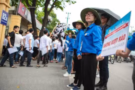 Sinh viên tình nguyện của trường Đại học Kinh tế quốc dân đứng sát nhau tạo thành hàng rào giúp các thí sinh nhanh chóng rời trường sau giờ thi. (Ảnh: Minh Sơn/Vietnam+)