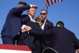 Cựu Tổng thống Donald Trump được mật vụ Mỹ hộ tống rời khỏi bục diễn thuyết trong cuộc vận động tranh cử ở thành phố Butler, bang Pennsylvania sau khi xảy ra vụ nổ súng, ngày 13/7. (Ảnh: THX/TTXVN')
