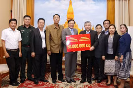 Đại sứ Nguyễn Bá Hùng trao cho Thứ trưởng Bộ Lao động và Phúc lợi xã hội Lào Padeumphone Xonthavy số tiền 50 triệu kip để giúp người dân Lào bị ảnh hưởng bởi lũ lụt nhanh chóng khắc phục và ổn định cuộc sống. (Ảnh: Phạm Kiên/Vietnam+)