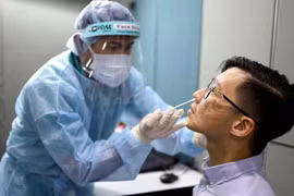 Nhân viên y tế lấy mẫu dịch xét nghiệm COVID-19 cho người dân tại Singapore ngày 30/10 vừa qua. (Ảnh: AFP/TTXVN)