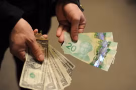 Đồng USD (trái) và đồng CAD (phải). (Ảnh: AFP/TTXVN)