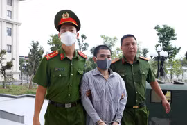 Lực lượng chức năng dẫn giải bị cáo Nguyễn Trung Huyên đến phiên tòa xét xử. (Ảnh: Phạm Kiên/TTXVN)