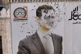 Bức ảnh chân dung Tổng thống Assad bị đạn xuyên nát tại Syria. (Nguồn: France 24)