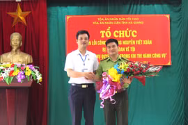 Phó Chánh án TAND tỉnh Hà Giang Trương Huy Huân tặng hoa cho ông Nguyễn Viết Xuân. (Ảnh: Minh Tâm-TTXVN)