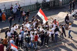 Người biểu tình Iraq phản đối Chính phủ tràn vào cây cầu al-Sinek để tiến vào vùng Xanh ở thủ đô Baghdad ngày 17/11. (Ảnh: AFP/TTXVN)