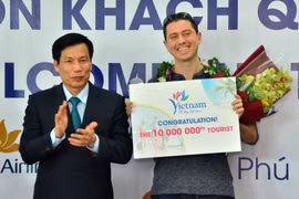 Bộ trưởng Bộ Văn hóa-Thể thao và Du lịch Nguyễn Ngọc Thiện tặng hoa, kỷ niệm chương cho ông Michael Tonge - du khách thứ 10 triệu đến Việt Nam trong năm 2016. (Nguồn: TTXVN)