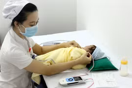 Nhân viên y tế sàng lọc khiếm thính cho sơ sinh tại Trung tâm Sàng lọc-chẩn đoán trước sinh và sơ sinh. (Ảnh: Dương Ngọc/TTXVN)