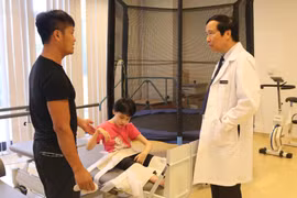 Giáo sư Nguyễn Thanh Liêm trao đổi, kiểm tra sức khỏe cho một bệnh nhân nhi. (Ảnh: T.G/Vietnam+)