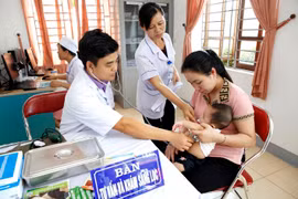 Nhân viên y tế khám sàng lọc trước khi tiêm chủng cho trẻ. (Ảnh: Dương Ngọc/TTXVN)