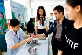 Nhân viên y tế xét nghiệm đường huyết cho người bệnh. (Ảnh: Dương Ngọc/TTXVN)