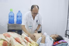 Phó giáo sư Đỗ Duy Cường khám cho một bệnh nhân điều trị viêm gan. (Ảnh: PV/Vietnam+)