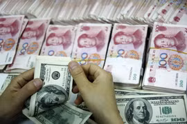 Đồng tiền giấy 100 đôla Mỹ (trên) và đồng 100 nhân dân tệ (phía dưới) tại một ngân hàng ở Hoài Bắc, tỉnh An Huy, Trung Quốc. (Nguồn: AFP/TTXVN)