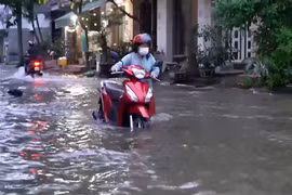 Người dân phải dắt xe bị chết máy qua dòng nước ngập trên đường Phú Thuận (Quận 7). (Ảnh: TTXVN phát)