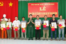 Lãnh đạo bộ đội biên phòng Sóc Trăng trao tặng cờ và ảnh bác Hồ cho ngư dân vùng ven biển Sóc Trăng. (Ảnh: Trung Hiếu-TTXVN)