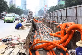 Thi công hạ ngầm tuyến cáp trên đường Lê Văn Lương, Hà Nội. (Ảnh: Hồng Kỳ/TTXVN)