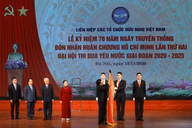 Phó Thủ tướng, Bộ trưởng Bộ Ngoại giao Phạm Bình Minh gắn Huân chương Hồ Chí Minh lên lá Cờ truyền thống của Liên hiệp các tổ chức hữu nghị Việt Nam. (Ảnh: Văn Điệp/TTXVN)