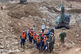 Lực lượng chức năng đưa thi thể nạn nhân ra khỏi hiện trường. (Ảnh: TTXVN phát)
