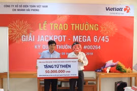 Anh Nguyễn Quốc Thịnh trao quà sau khi nhận giải Jackpot. (Ảnh: Vietlott)